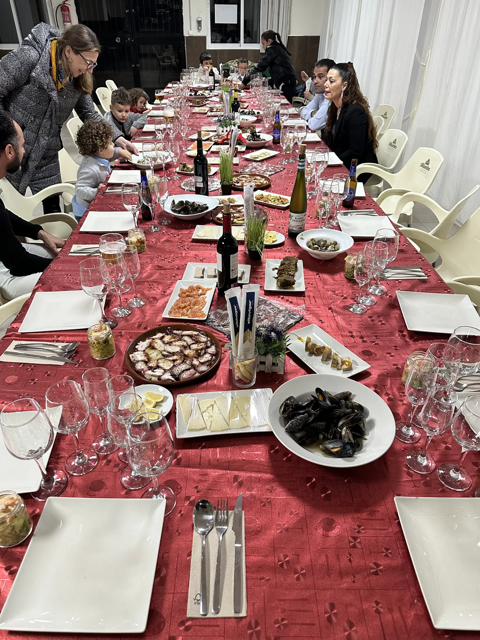 dining table(0.90), bowl(0.84), person(0.81), person(0.76), bottle(0.75), person(0.72), bottle(0.72), person(0.69), bottle(0.69), person(0.65), wine glass(0.64), fork(0.59), bowl(0.56), wine glass(0.54), chair(0.53), wine glass(0.53)